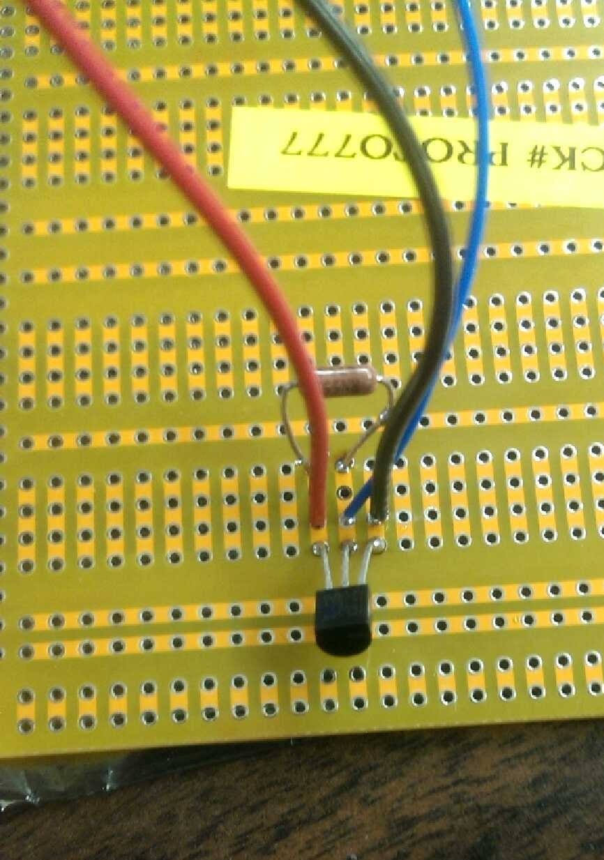 A temperature sensor and a resistor soldered to a breadboard, with wires coming out